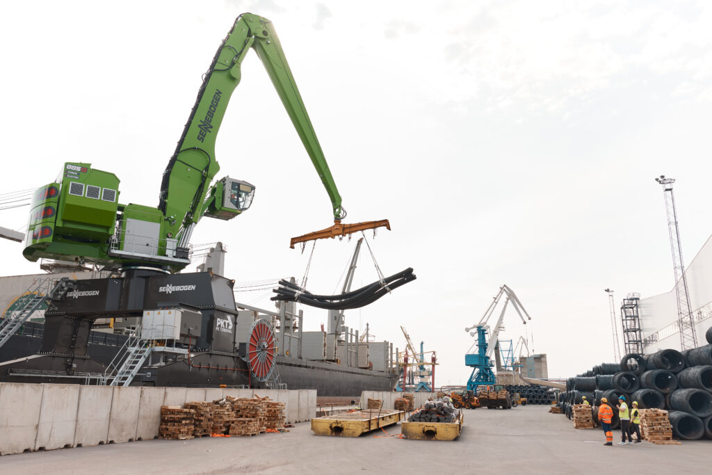 Forklifts and cranes handle steel coils along the unloading line.